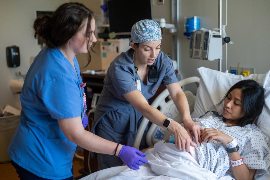 A nurse and nursing student attend to a pregnant woman in the labor and delivery ward