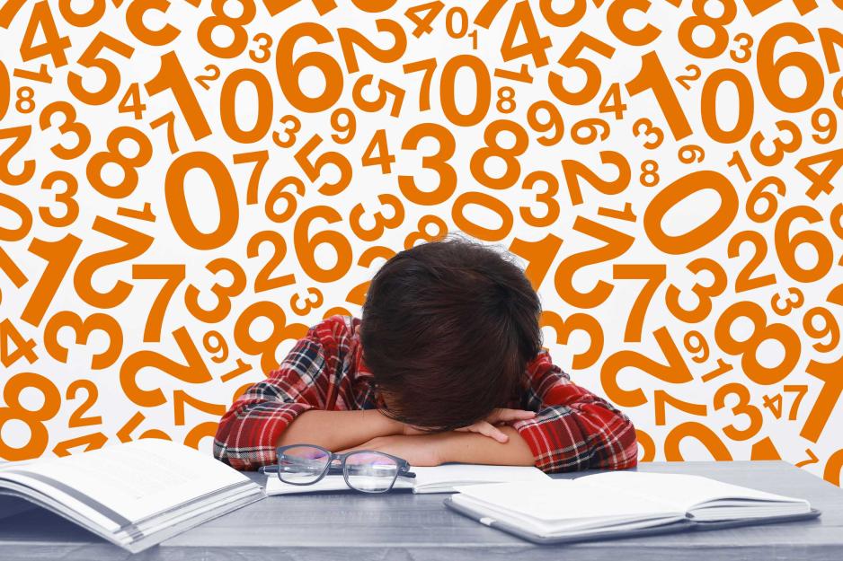 student laying head on desk surrounded by numbers and books