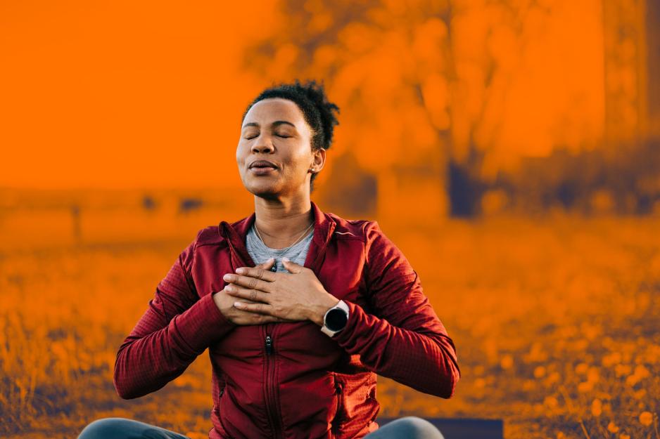 An illustration of women meditating outdoors against an orange, autumn-like background.