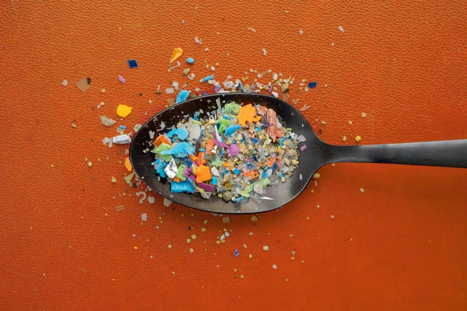 A spoon overflowing with tiny pieces of plastic