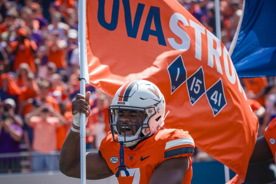 Candid portrait of Mike Hollins carrying the UVA Strong flag during the match day.y