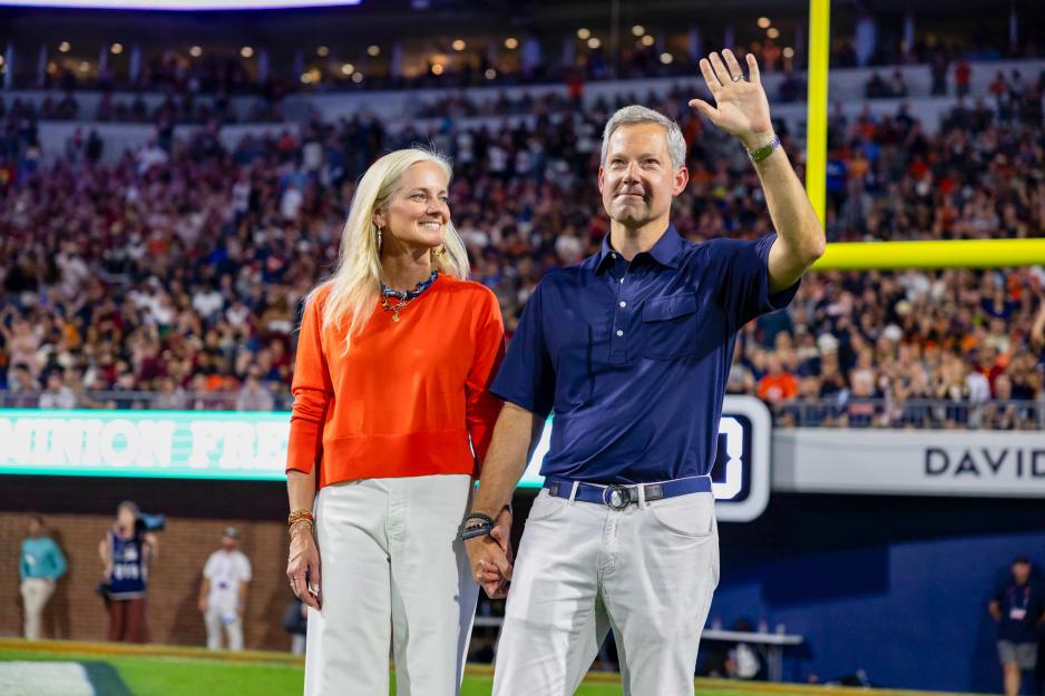 Ryan Odom and Lucia Odom waving to the crowd from the field of Scott Stadium