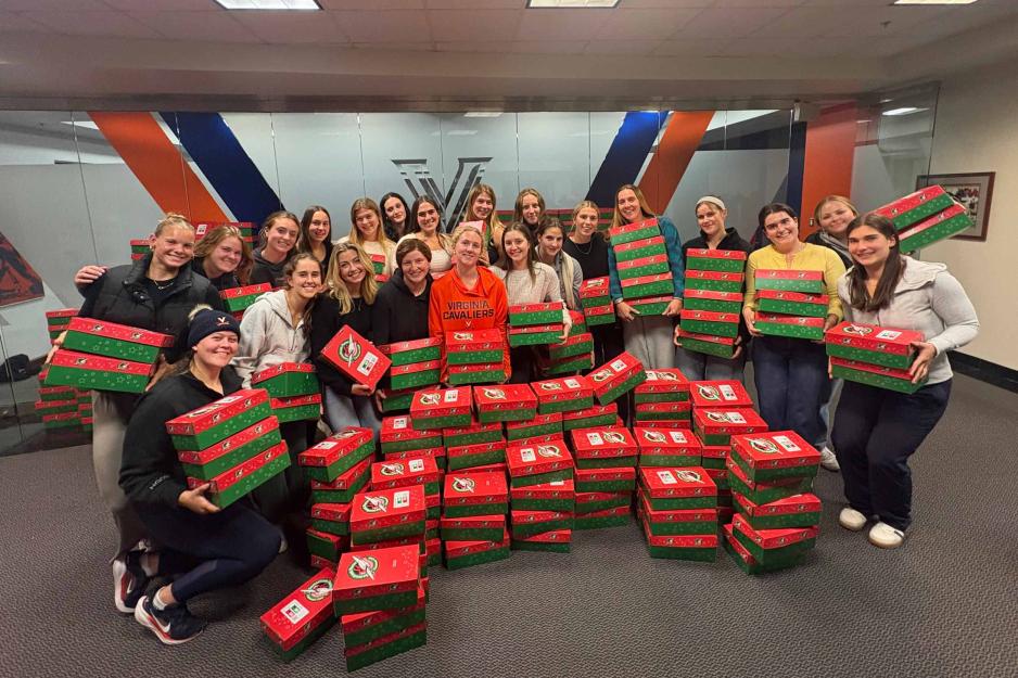 the UVA women's rowing team posing for a photograph behind 133 shoeboxes.