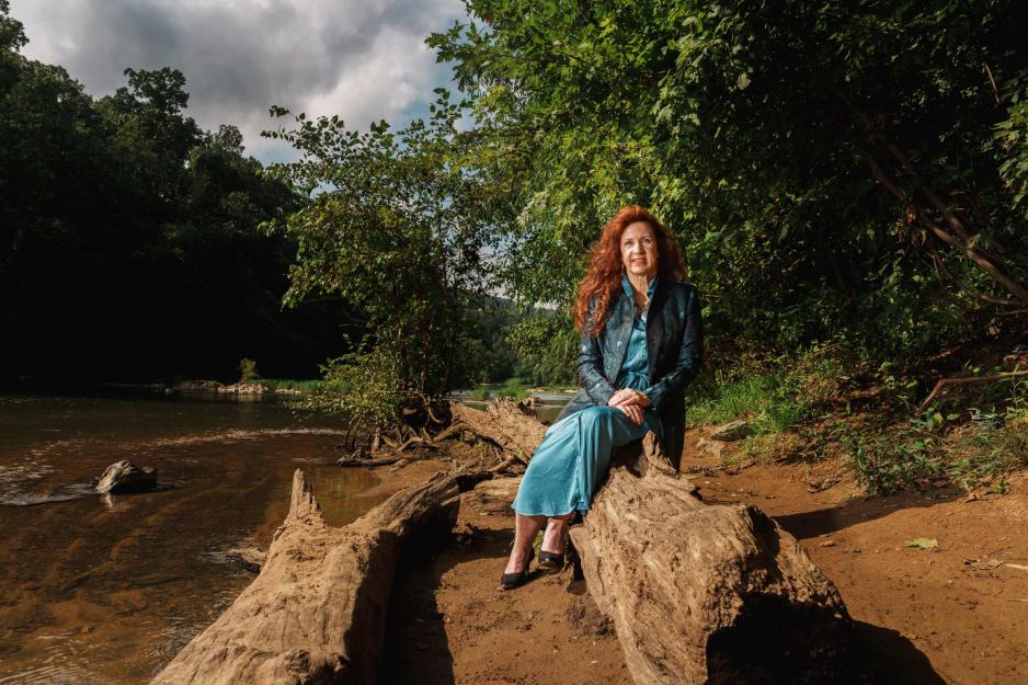Robin Dunbar sitting on a log on the shore of the Elizabeth River