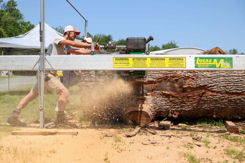 Portrait of Sawyer Wade Cotten guides a 72-inch chainsaw bar through a 48-inch-wide, 11-foot-long white oak log, slicing off a 2 1/2-inch slab