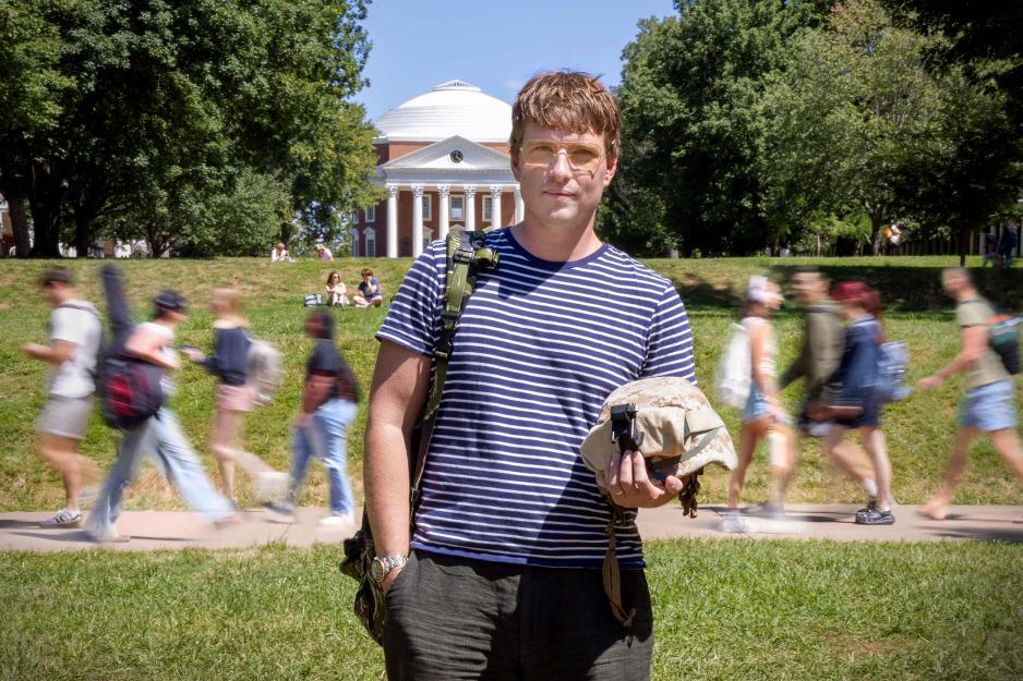 Stephen Cantry wearing a Marines backpack and headwear stands for a photo on the Lawn in front of the Rotunda at UVA on a bright afternoon