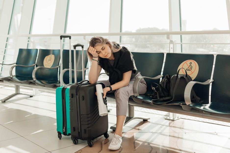 tired person sitting at an airport gate with suitcases