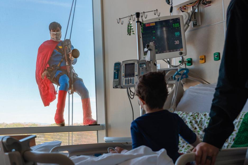 From behind a patient  looking out the window of the UVA Health Children’s Hospital looking at Superman washing the window