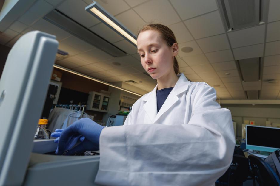 Katie Nichols in a laboratory at UVA loading samples into a centrifuge.