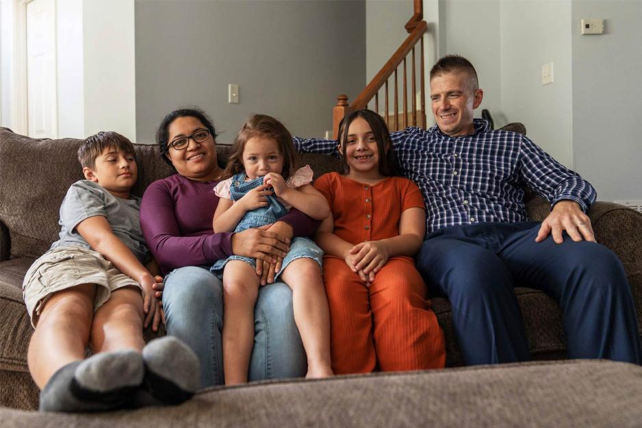 A family of five snuggles together on a couch