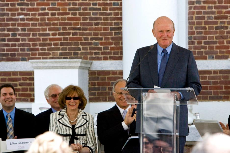 Robertson stands at a plexiglas podium and smiles at an audience.