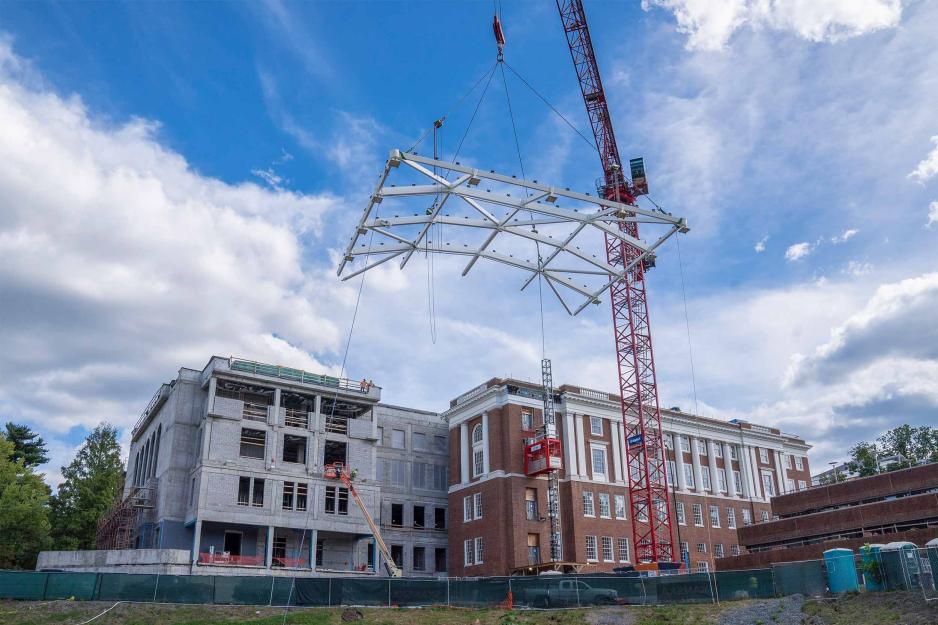 A crane lifts a large, white metal frame