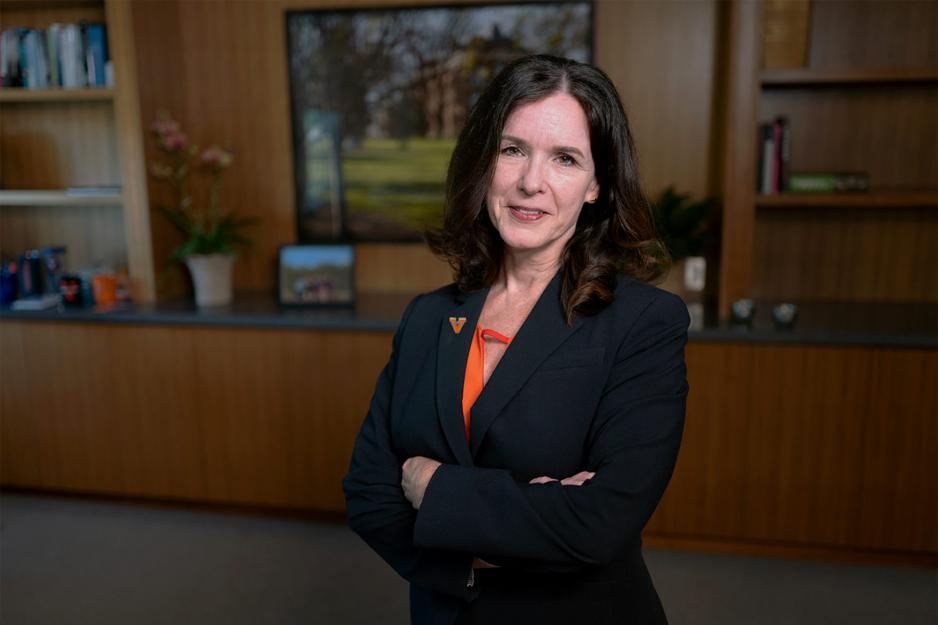 Christa Acampora stands in an office with her arms crossed, smiling at the camera