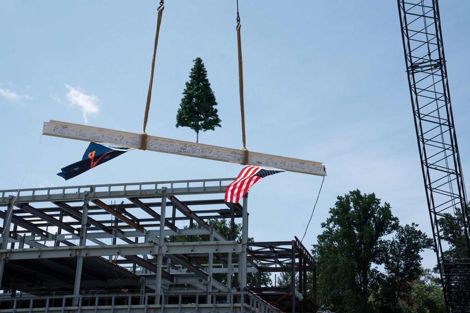 A crane lifts a steel girder with a Christmas tree on top