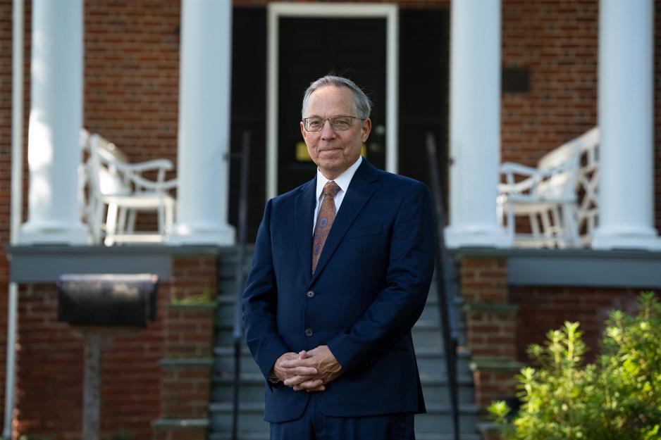 Eric Brandt stands with hands folded in front of a brick building with white columns. 