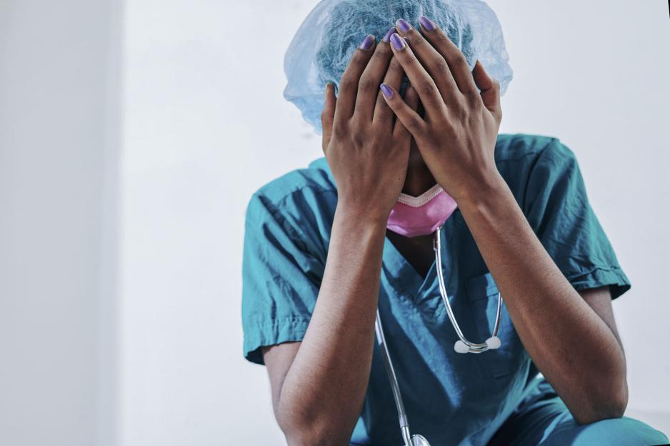 Nurse holding her head looking down