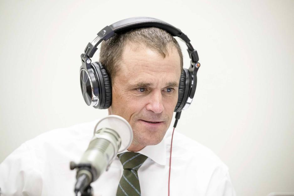 Jim Ryan wears headphones and speaks into a microphone