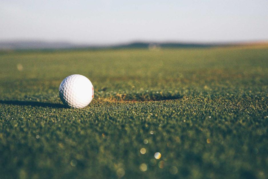 A golf ball sits less than an inch from the hole
