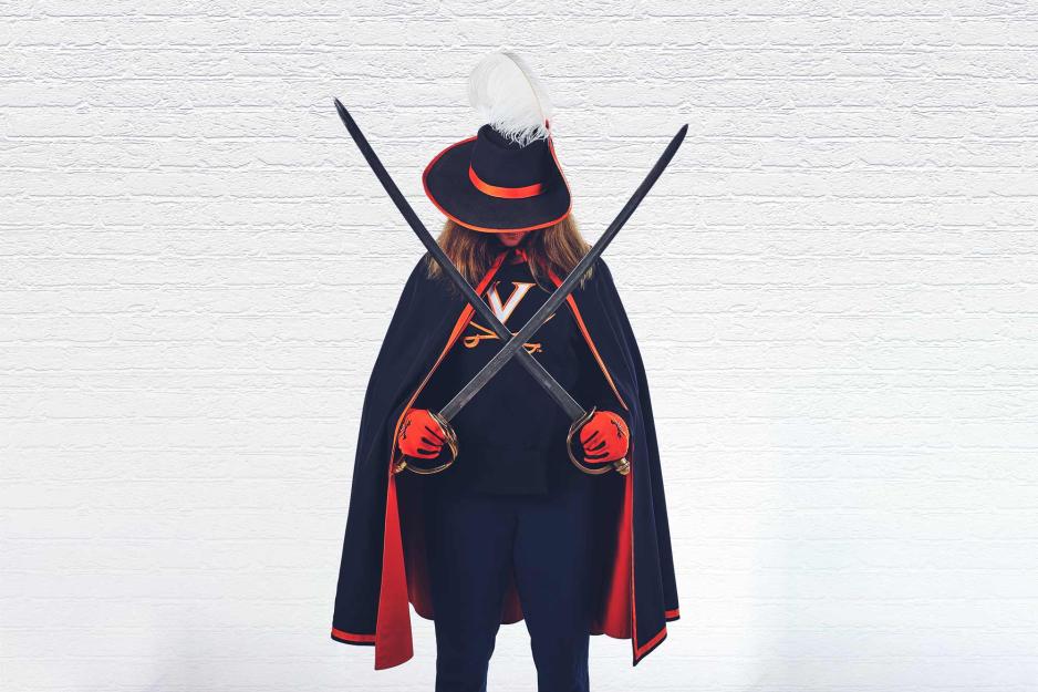 A woman in a blue cape hides her eyes under a feathered cap, holding crossed sabres