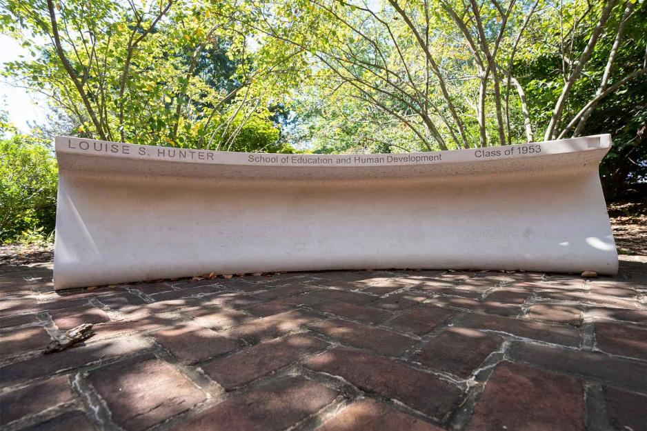 A curved concrete bench engraved with "Louise S. Hunter, School of Education and Human Development, Class of 1953"