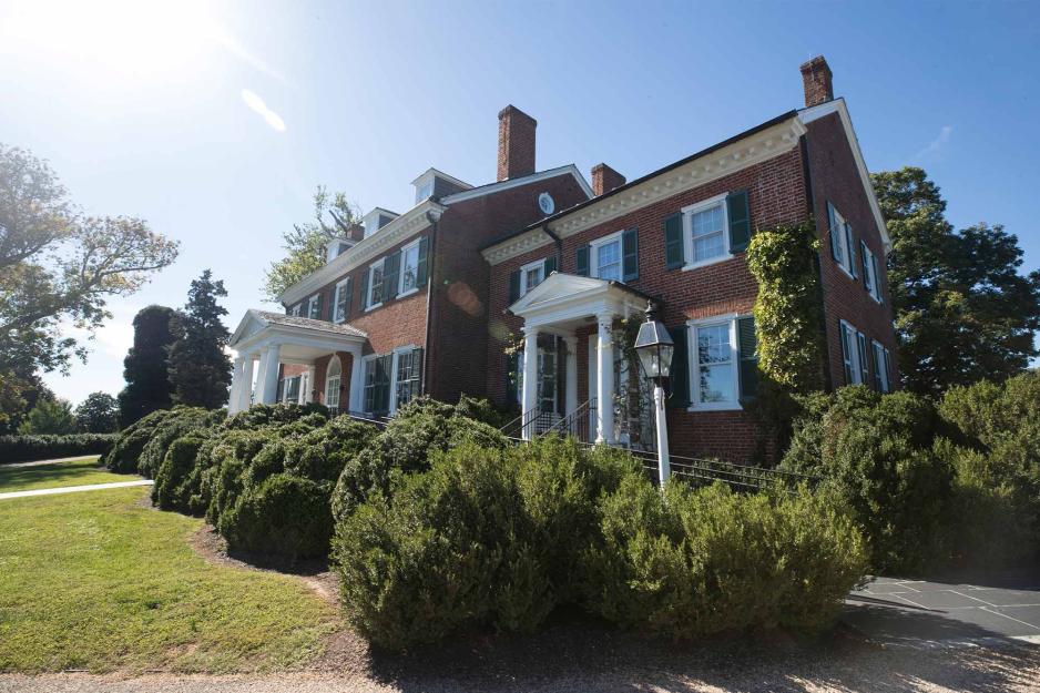 The sun shines on a large colonial brick house