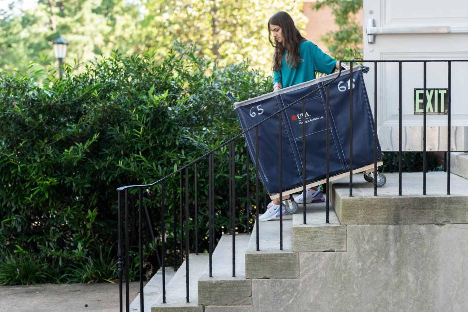 A woman moves a blue moving cart down a short flight of stairs