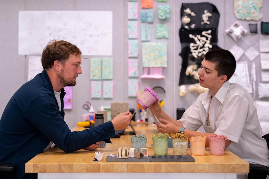 Professor and Student Research Assistant sit at a table and talk