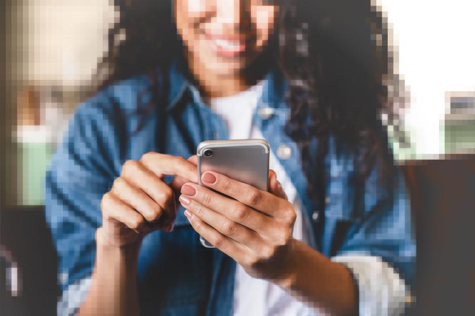 A photo of a teen on their cell phone where everything but the phone has been pixilated and blurred