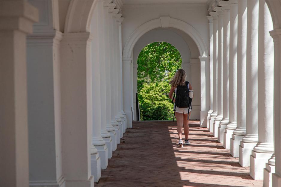 Student walking down an outdoor hall on grounds