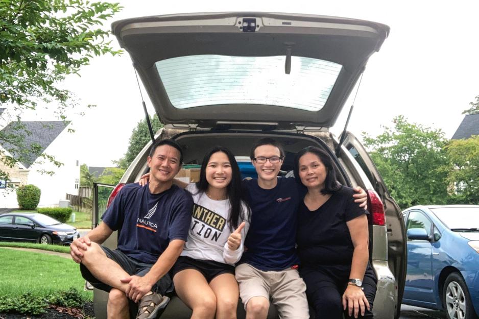 Justin Vinh sitting in the hatchback of a car with his parents and sister