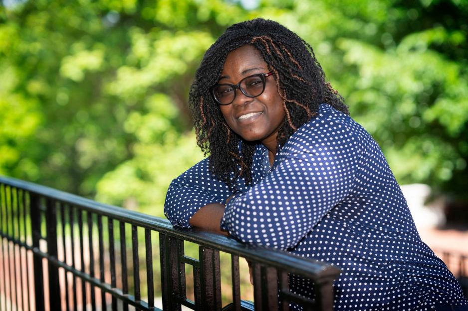 Nana Boateng leans against an iron railing and smiles at the camera