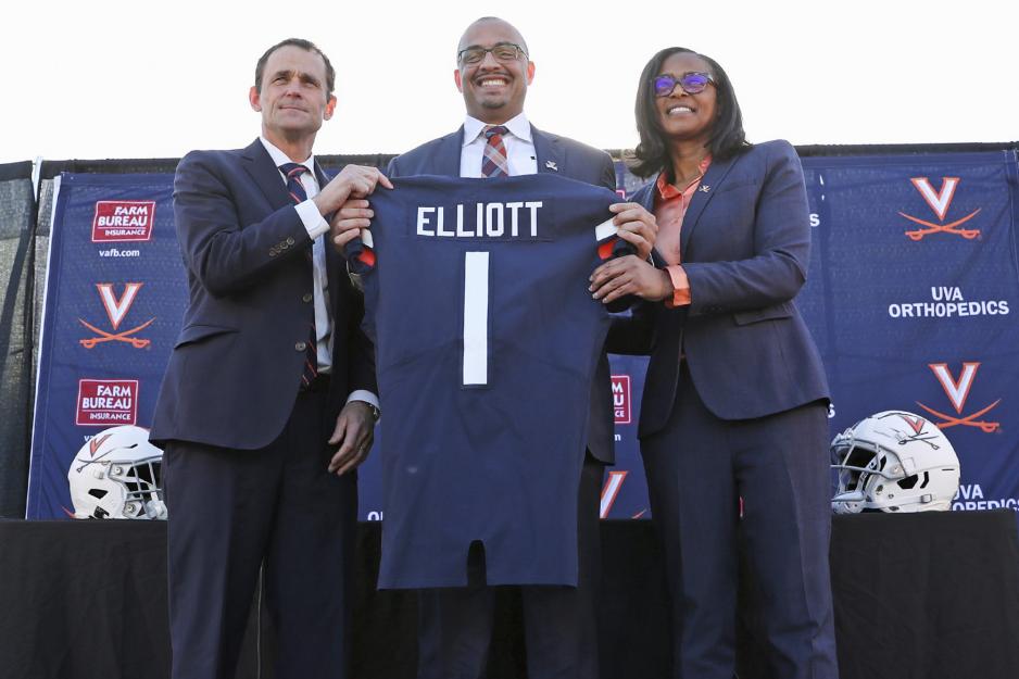 UVA President Jim Ryan, left, and Athletic Director Carla Williams, right, and elliot in the middle holding a jersey with #1 and his name on the back