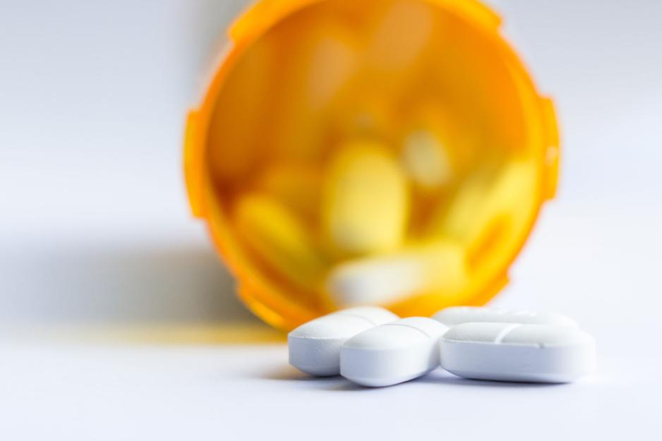 A prescription pill bottle spilling white pills