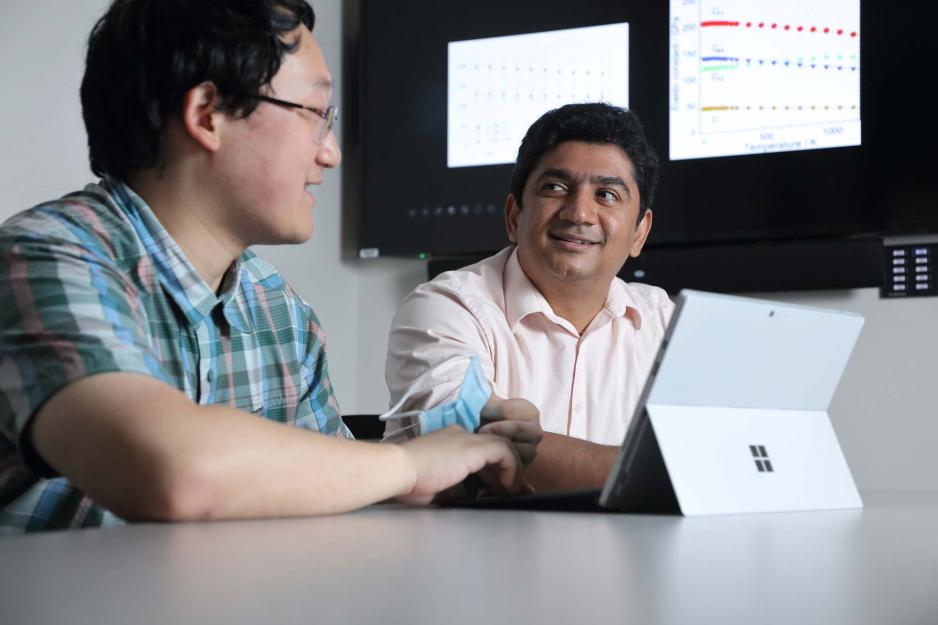 Two smiling students work together on a laptop