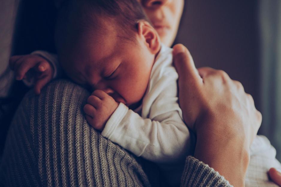 A newborn baby sleeping on her mother's shoulder