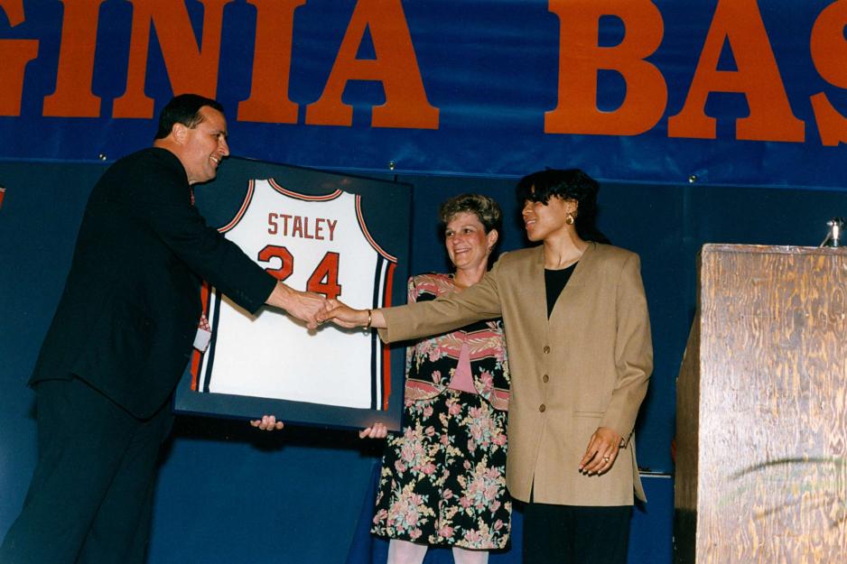 Dawn Staley on stage with Debbie Ryan accepting a framed basketball jersey