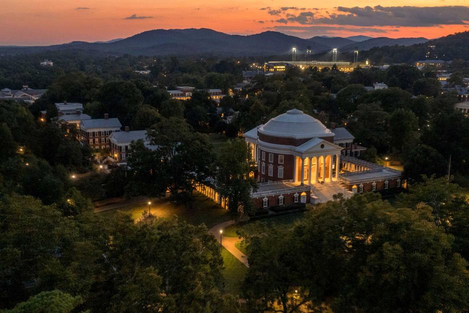 An aerial view of the Rotunda and the blue ridge as the sun sets over the ridge