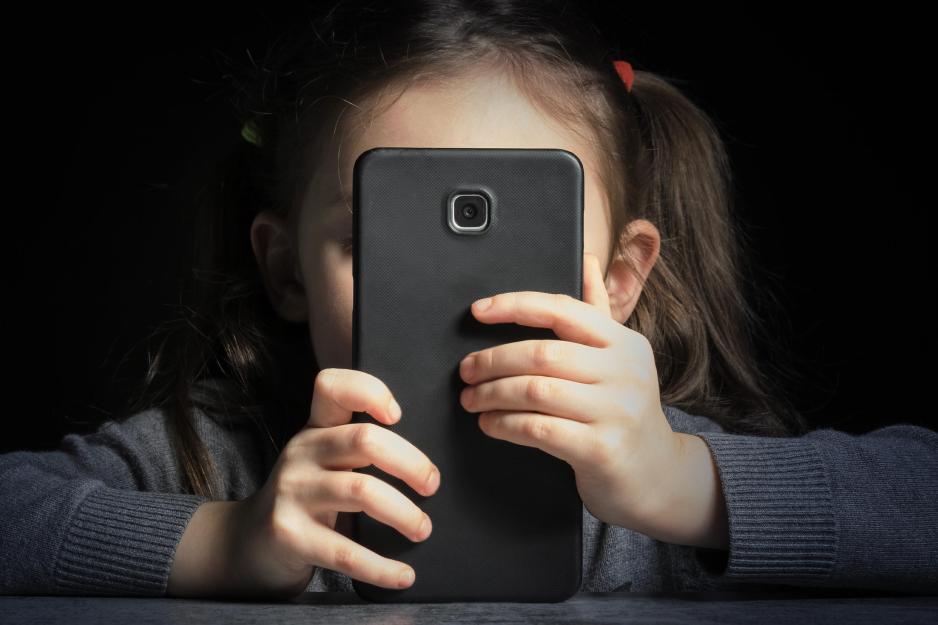 A child holds a phone over their face playing on it