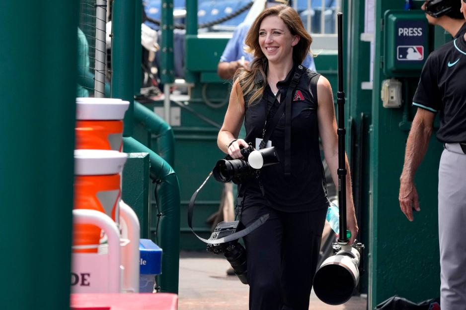 Kelsey Grant walking out with various camera gear to capture a game