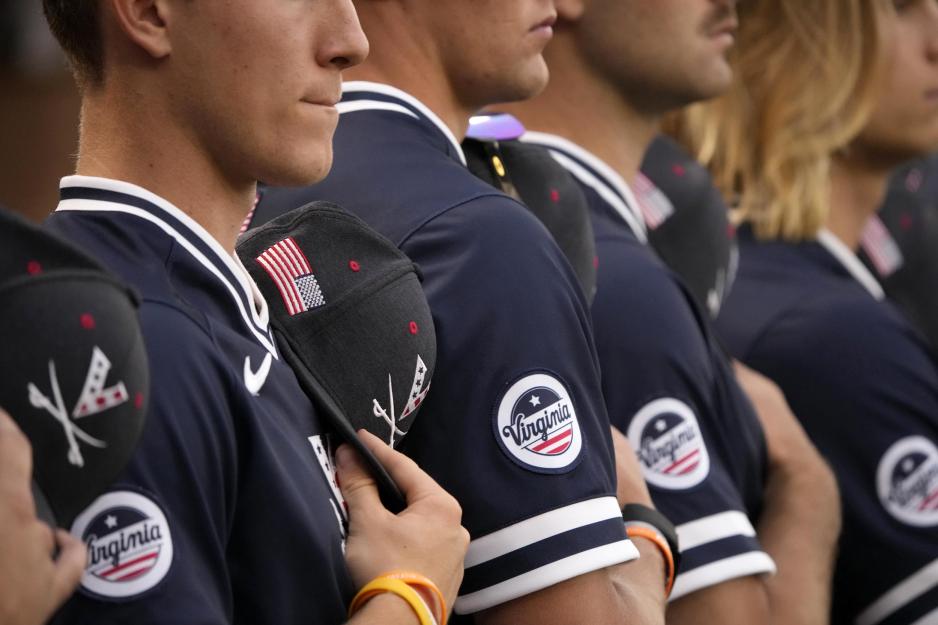 Baseball players hold hats over hearts as the National Anthem plays