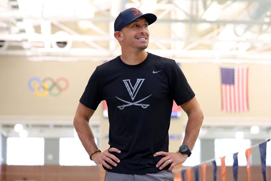 Todd DeSorbo smiling with the Olympic rings and American flag behind him at a pool.