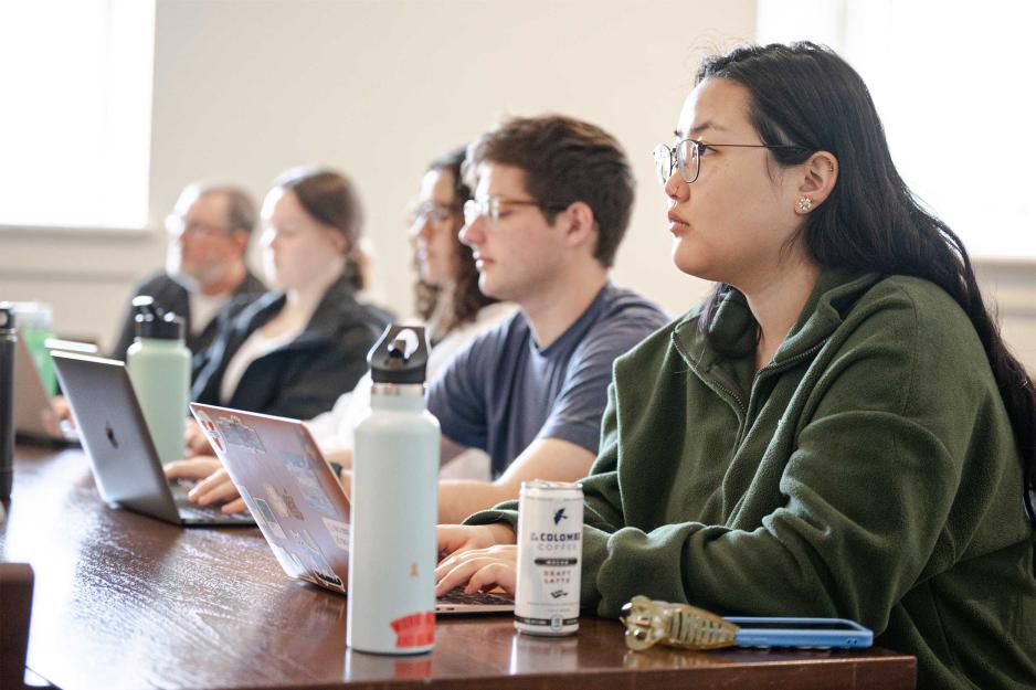 A group of students sitting at a table with laptops open