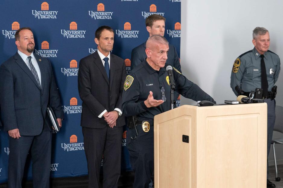 UVA Executive leadership stand behind Tim Longo as he speaks at press conference podium
