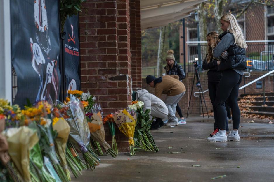 Students looking a memorial for the victims that is surrounded by flowers