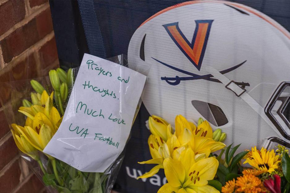 Memorial made of flowers, image of UVA Football helmet and a letter that reads, Prays and thoughts.  Much Love UVA Football