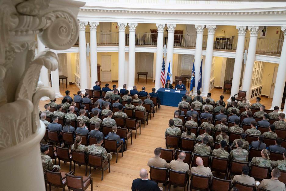 Air Force C.O.S sitting at a tale speaking to a crowd