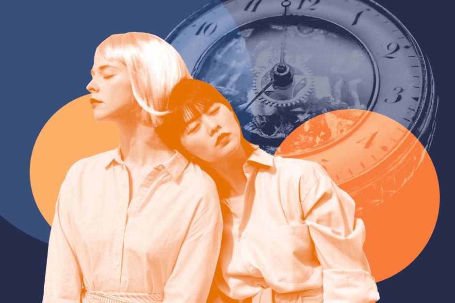 A teenage girl leans her head on the shoulder of another teenage girl, a vintage clock in the background