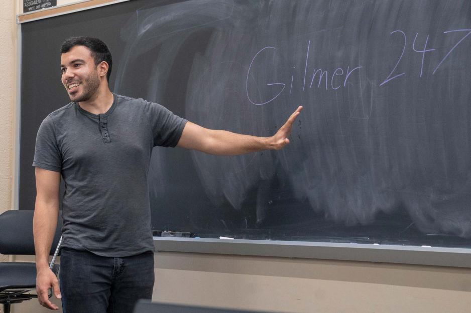 Candid portrait of Nicholas James in front of the black board in his classroom