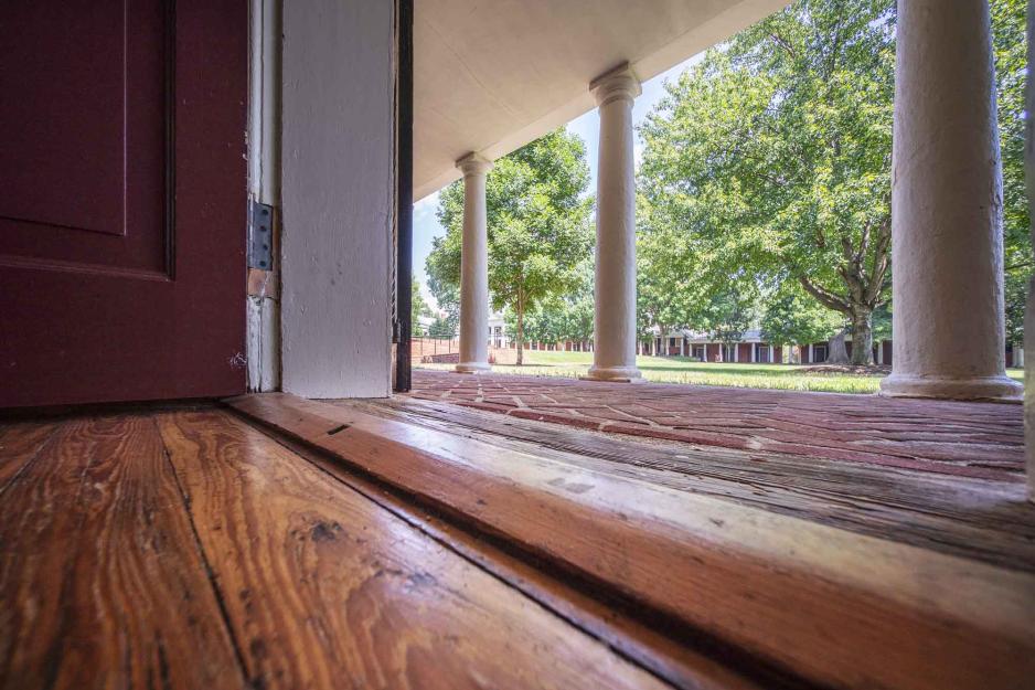 Wood floor at the entrance of the Lawn room facing the outside to the brick walkway in front