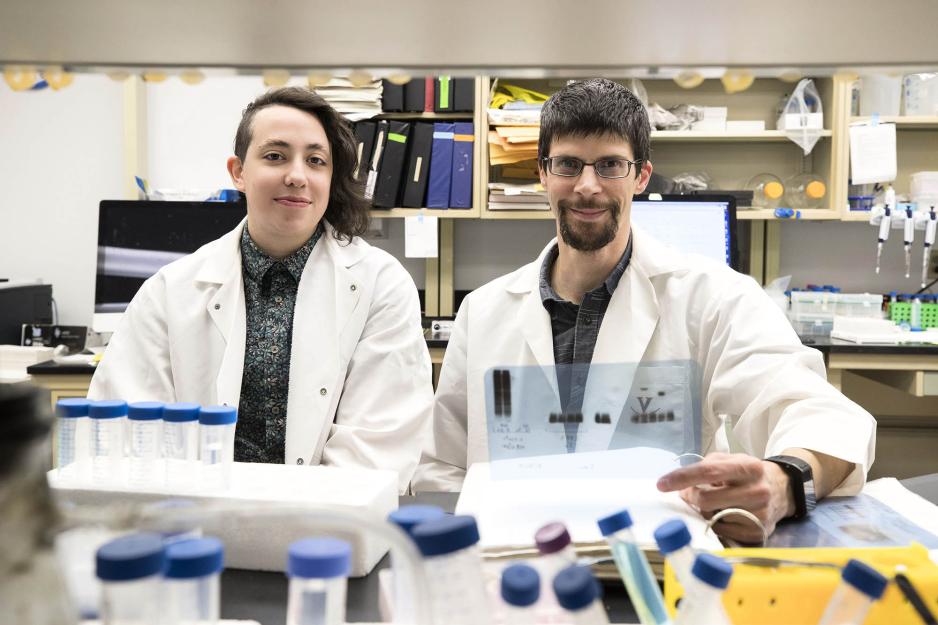 Dorian Rosen, left, and Alban Gaultier, right sit at a table in the lab together working on test tubes and looking through a binder